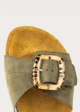 Sandalia plana verde militar con tira ancha de ante y hebilla grande de resina carey. Suela ergonómica de corcho y base de goma.