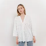 Camisa blanca de diseño suelto con cuello en V y mangas 3/4. Presenta detalles calados y bordados en un patrón geométrico.
