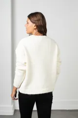 Buzo de punto color blanco, de corte holgado y cuello redondo, con diseño de flores aplicadas con detalles de mostacillas bordadas.