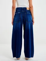 Jeans de mezclilla azul oscuro, corte ancho y tiro alto, con cinco bolsillos y terminación deshilachada en el ruedo.