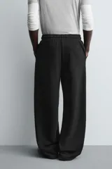 Pantalón jogger de corte relajado y pernera ancha, confeccionado en tejido de algodón con interior perchado. Presenta cintura elástica con cordón interior, bolsillos laterales y un bolsillo trasero de plastrón.