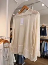 Sweater de punto calado color beige, de manga larga y calce relajado, con musculosa interior incorporada que presenta terminación bordada en el ruedo.