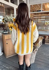 Sweater de lana color crema con rayas verticales anchas color amarillo mostaza, de corte holgado y cuello redondo. Tejido a mano.