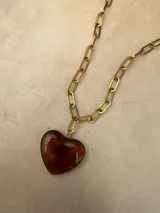Collar de cadena de eslabones dorados con dije de corazón de resina pulida. Disponible en color blanco y color ámbar.