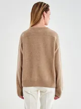 Sweater de tejido de punto color gris claro, con cuello redondo, mangas largas y terminaciones acanaladas en puños y ruedo.