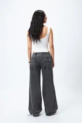 Pantalón jean ancho color gris oscuro, con elástico en la cintura, cordones ajustables en los bajos y grandes bolsillos laterales y traseros.