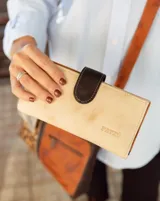 Billetera larga de cuero color beige con cierre de broche marrón y logo grabado.