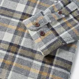 Camisa de franela a cuadros color blanco, gris y ocre, de manga larga, con cuello clásico, cierre frontal con botones y dos bolsillos con solapa abotonada en el pecho.