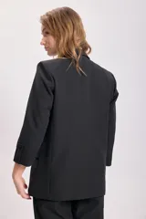 Blazer negro de corte sastrero con mangas tres cuartos, solapas clásicas y cierre frontal con un botón. Presenta bolsillos laterales con solapa.