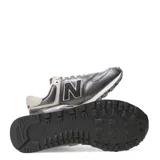 Championes urbanos New Balance modelo 574, color gris oscuro metalizado con detalles en beige claro. Presentan el logo 'N' en negro con borde blanco y cordones beige.