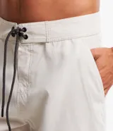 Bermuda de hombre estilo surf, color beige, con cintura fija, cordón contrastante y bolsillo trasero con tirador.