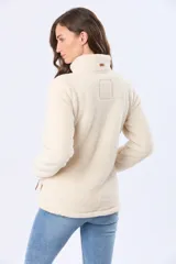 Campera de sherpa color beige con cierre frontal, cuello alto y bolsillos laterales con detalles en cuero sintético.