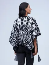 Poncho tejido con diseño tribal en blanco y negro, terminación con borlas.