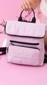 Mochila de nylon capitoneada color celeste, con diseño acolchado en cuadrícula. Posee un compartimento principal con cierre y solapa, además de dos bolsillos frontales con cierres negros a la vista.