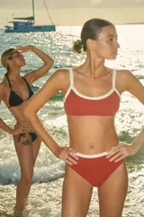 Conjunto de bikini color ladrillo con textura, compuesto por un corpiño cuadrado con breteles regulables y collareta blanca, y una bombacha de tiro alto con collareta blanca.