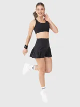 Falda negra con short integrado, diseñada con cintura alta y ruedo plisado. Incluye bolsillo en el short interno.