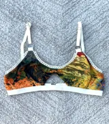 Corpiño blanco de algodón con detalle de puntilla y abertura en el centro.