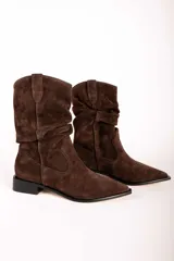 Bota de caña media estilo western, confeccionada en gamuza color marrón oscuro. Presenta un diseño con efecto arrugado en la caña, puntera fina y taco bajo cuadrado.