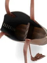 Matera de cuero color marrón con diseño estructurado, costuras laterales decorativas en color claro, base reforzada con remaches metálicos y detalle de borla colgante. Incluye correas largas para llevar al hombro.