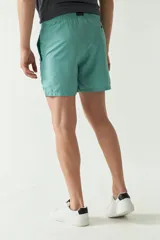 Short de baño liso con cintura elástica y cordón ajustable. Cuenta con dos bolsillos laterales, un bolsillo trasero y logo bordado. Confeccionado en tela ligera de secado rápido.