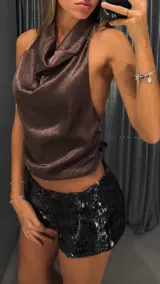 Top de cuello halter con escote drapeado, confeccionado en tela satinada con textura sutil en color chocolate. Diseño sin mangas y espalda descubierta con ajuste lateral.