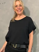 Blusa negra de corte holgado, con cuello redondo y mangas cortas con vuelta.