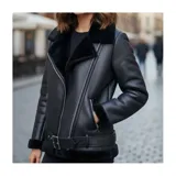 Campera estilo biker de United Uy, confeccionada en gamulán negro con interior de corderito térmico. Presenta cierre frontal asimétrico, bolsillos laterales con cierre y cinturón ajustable en la cintura.