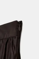 Falda midi marrón oscuro, con diseño fluido y voluminoso, tiro alto y detalles de bordados a tono en el ruedo.