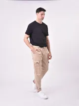 Pantalón jogger negro con cintura elástica y cordón ajustable, bolsillos laterales y bolsillos cargo con solapa en los muslos. Los tobillos tienen puños elásticos.