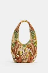 Bolso de hombro con diseño estructurado, decorado con intrincados bordados de abalorios, cuentas y apliques en tonos tierra, verde y crema. Presenta un asa integrada y cierre mediante botón imantado.