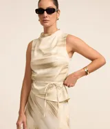 Blusa sin mangas de poliéster satinado con cuello alto y abertura en la espalda. Presenta un estampado abstracto en tonos beige y lazo en la cintura.