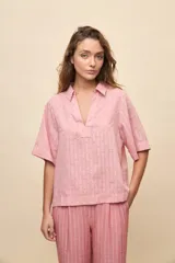 Blusa celeste de manga corta con cuello camisero y escote en V, confeccionada en tejido liviano con textura sutil y estampado de lunares.