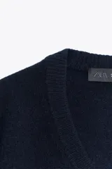 Jersey de punto liso confeccionado en lana 100%, con cuello en pico y manga larga. Presenta acabados en rib en puños y bajo.