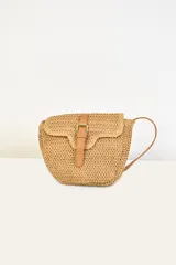 Bolso bandolera de paja color beige con correa de cuero marrón y cierre con hebilla.