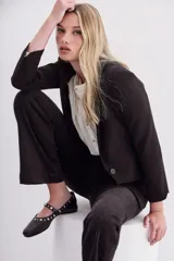 Balerinas negras de cuero con tira sobre el empeine y remaches de níquel de distintos tamaños.