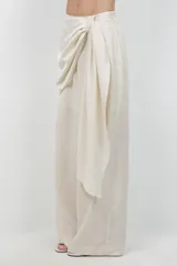 Pantalón beige de pierna ancha, confeccionado en tela suave con finos destellos dorados, diseño forrado y sobre tela drapeada a modo de cinturón.