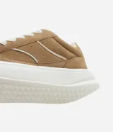 Championes de estilo skater para hombre, confeccionados en poliuretano color marrón oscuro. Poseen punta redonda, caña baja y suela de plataforma blanca. Destacan por sus cordones anchos tipo fat lace y detalles laterales en contraste.