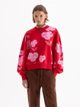 Buzo rojo de calce amplio, confeccionado en tela de punto con estampado de cerezas en color rosado. Presenta cuello redondo, puños y bajo en tejido liso a tono.
