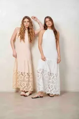 Vestido largo beige con cuello halter y detalle de broderie calado en el dobladillo inferior.