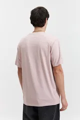 Remera de manga corta color rosa pálido con escote redondo y fit regular. Presenta un arte estampado en relieve en el centro del pecho con texto circular.