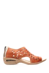 Sandalia baja de cuero color beige con diseño calado de círculos de distintos tamaños en la capellada. Cuenta con una suela de goma con cámara de aire en el talón y cierre posterior.