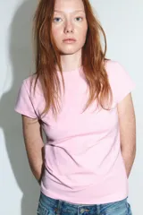 Camiseta rosa claro de manga corta y cuello redondo, con un diseño de dos corazones en relieve a tono sobre el frente.