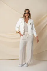 Chaqueta blanca de cuero vegano con corte entallado, cuello solapa, cierre asimétrico con cremallera metálica dorada y mangas 3/4 con puños estampados.