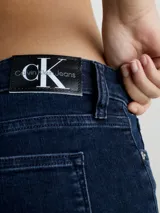 Jeans ajustados de mezclilla elástica color azul oscuro puro, con tiro medio y pierna estrecha. Presentan un diseño clásico de cinco bolsillos y bragueta con cremallera.