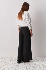 Pantalón wide leg de color negro, con cintura de tiro alto, lazo ajustable y caída fluida.