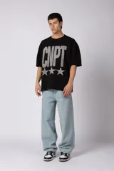 Remeron de corte oversize color negro, con estampa frontal en color gris desgastado que incluye el texto 'CNPT' y tres estrellas. Presenta cuello redondo y mangas cortas amplias.