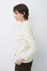 Polera de tejido de punto fino en color beige, con cuello alto y mangas largas con puños acanalados.