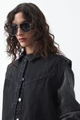 Chaleco de jean en tono celeste claro, con corte recto, cuello camisero, cierre frontal con botones metálicos y costuras visibles.