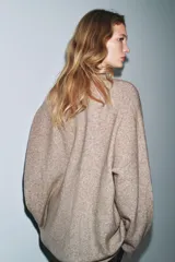 Jersey oversize color beige melange, confeccionado con lana, con cuello en V y manga larga.