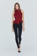 Corset bordó de cuello halter con hombros descubiertos, confeccionado con combinación de tejidos con patrón floral, detalles de volados en las sisas y bajo en peplum. Cuenta con cierre en la espalda con cremallera.